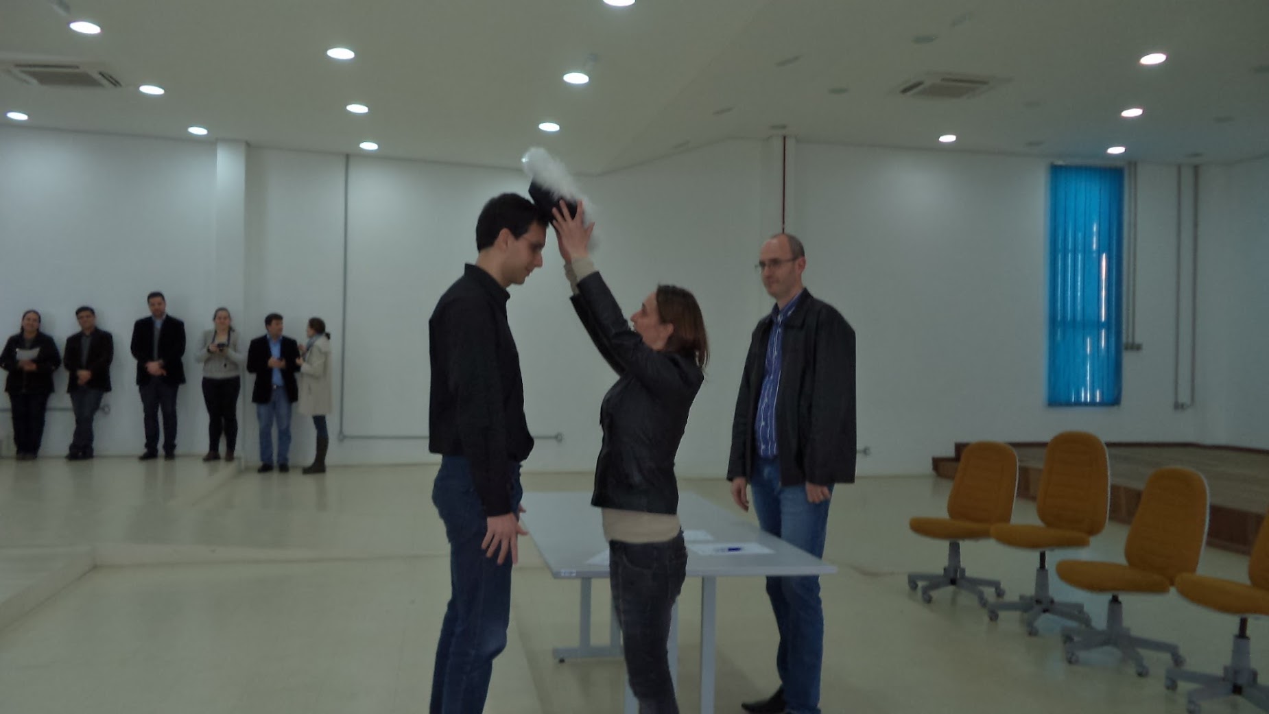 A man receiving a graduation hat by a woman.